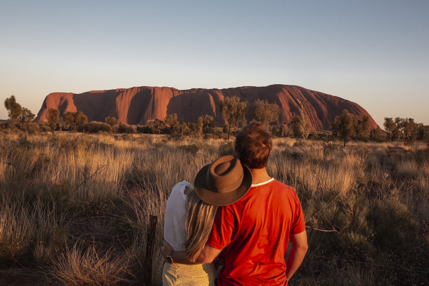 Couple devant Uluru au coucher du soleil, dans le centre de l'Australie