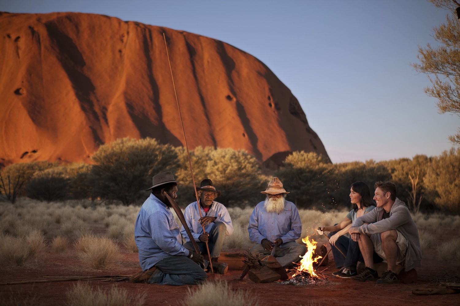 Aborigène au coucher du soleil autour du feu de camps à Uluru